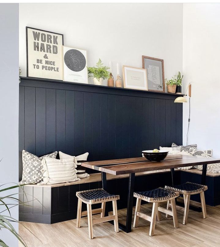 a dining room table with four chairs and a bench in front of it, along with pictures on the wall