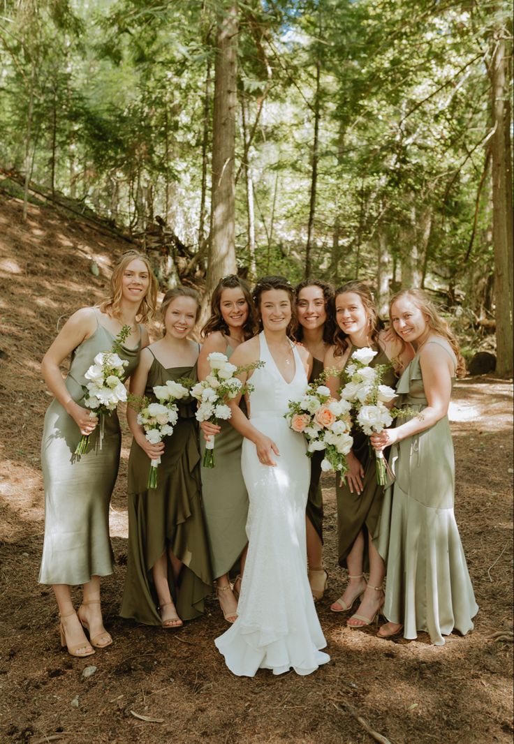 a group of women standing next to each other holding bouquets in their hands and posing for the camera