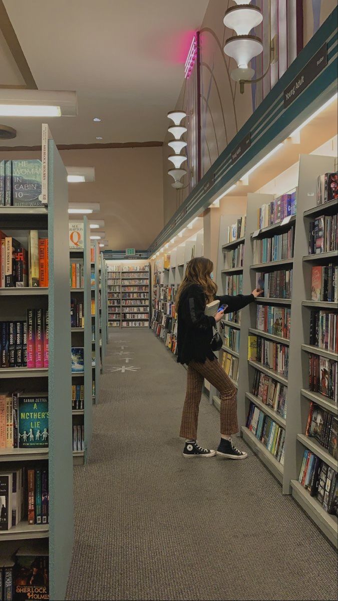 a woman standing in front of a book shelf filled with books