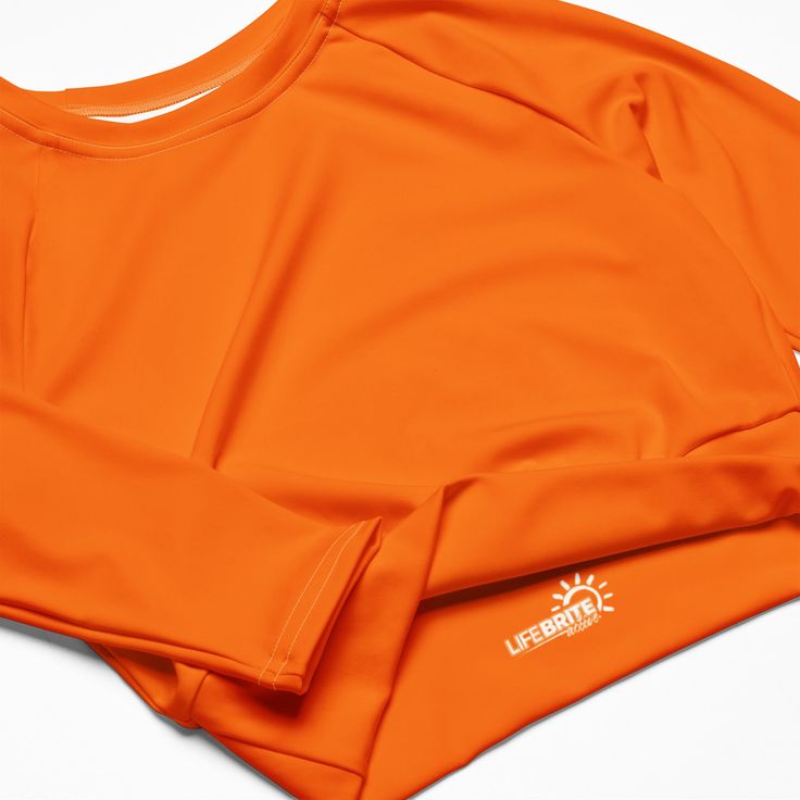 Fall in love with this versatile piece of eye-catching activewear. Our eco-friendly always bright orange cropped rash guard –made with recycled polyester and elastane– is the perfect choice for swimming, sports, or athleisure outfits. The long sleeves and cropped cut provides just enough coverage while the UPF 50+ rated material helps block the sun’s harsh UV rays. Stand out in confidence and comfort all year long in our “wear anywhere” cropped top. .: Made with 81% REPREVE recycled polyester, 1 Orange Yoga Tops, Orange Athleisure Tops For Sports, Orange Stretch Yoga Tops, Orange Stretch Sports Tops, Stretch Orange Yoga Tops, Orange Stretch Tops For Yoga, Orange Stretch Tops For Sports, Stretch Orange Tops For Sports, Orange Athleisure Activewear For Summer