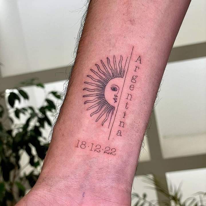 a man's arm with a sun tattoo on it and the date in roman numerals