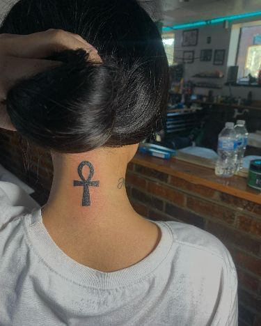 a woman with a tattoo on her neck and behind her head is a brick wall