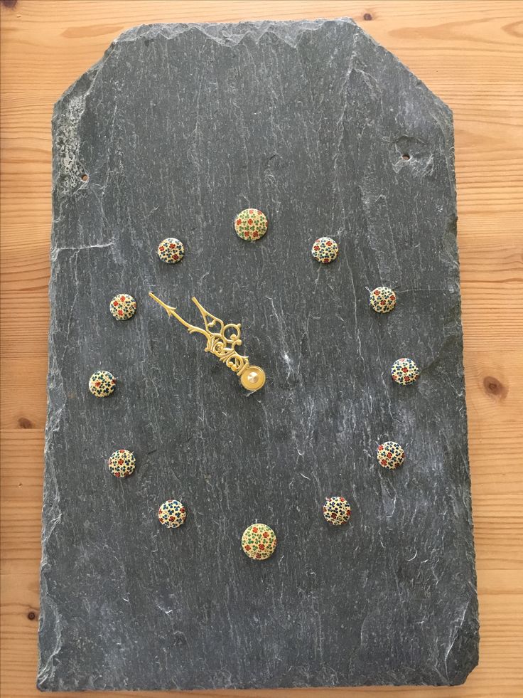 a clock made out of stones with gold colored beads