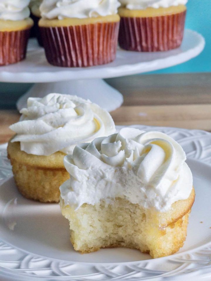 two cupcakes with white frosting sitting on a plate