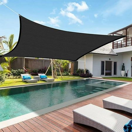 an outdoor area with a pool, lounge chairs and a large black shade over it