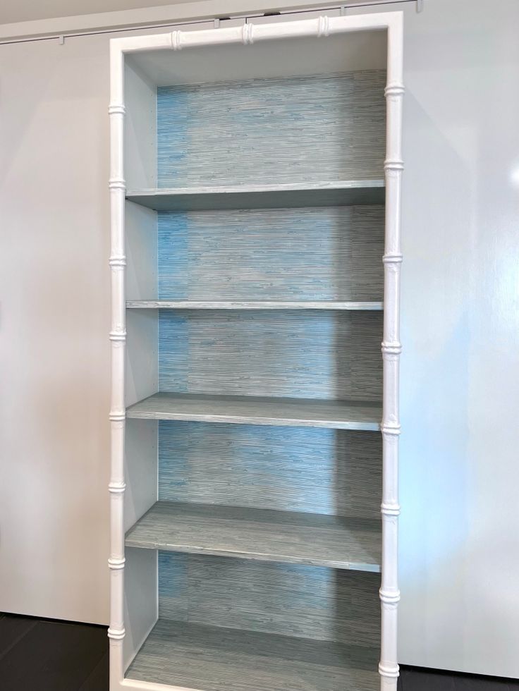 an empty white bookcase in the corner of a room