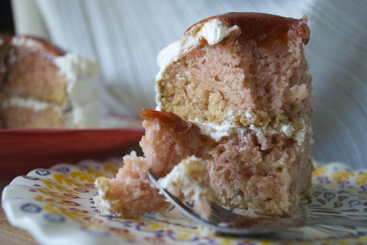 a piece of cake on a plate with a fork in it and someone's hand