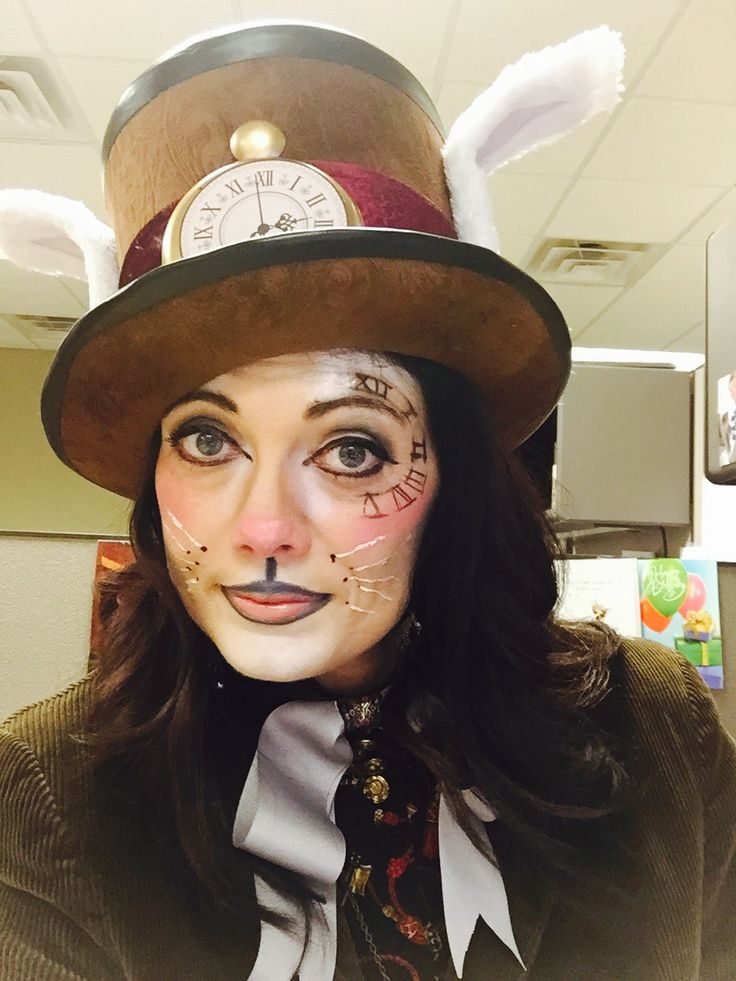 a woman wearing a top hat with feathers on her head and face painted like a rabbit