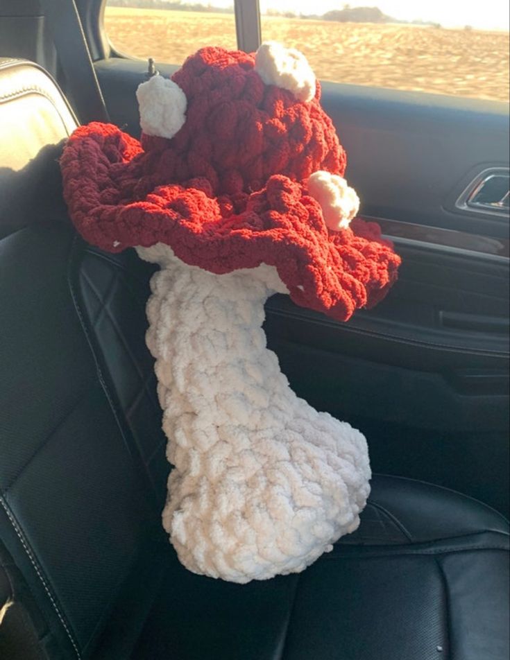 a crocheted red and white hat sitting on the back seat of a car