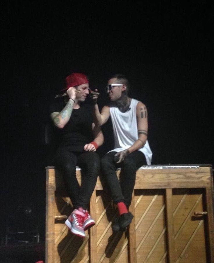 two young men sitting next to each other on top of a wooden bench in the dark