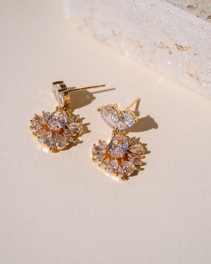 Introducing our latest addition to the collection - the exquisite Lily Crystal Earrings! These stunning earrings are designed to elevate any outfit with their breathtaking radiance and timeless elegance. The earrings feature delicate crystal detailing that is perfectly arranged to reflect light and create a sparkle that will catch everyone's eye! Crafted with exceptional attention to detail, the Lily Crystal Earrings are versatile enough to be paired with any outfit, from formal dresses to casua Elegant Sparkling Crystal Cluster Earrings, Cubic Zirconia Sparkling Stones Drop Earrings, Dazzling Bridal Drop Earrings With Sparkling Stones, Elegant Sparkling Cubic Zirconia Cluster Earrings, Crystal Cluster Drop Earrings With Sparkling Stones, Elegant Crystal Cluster Dangle Earrings, Elegant Sparkling Flower Drop Earrings, Delicate Cubic Zirconia Earrings For Party, Elegant Sparkling Flower Earrings