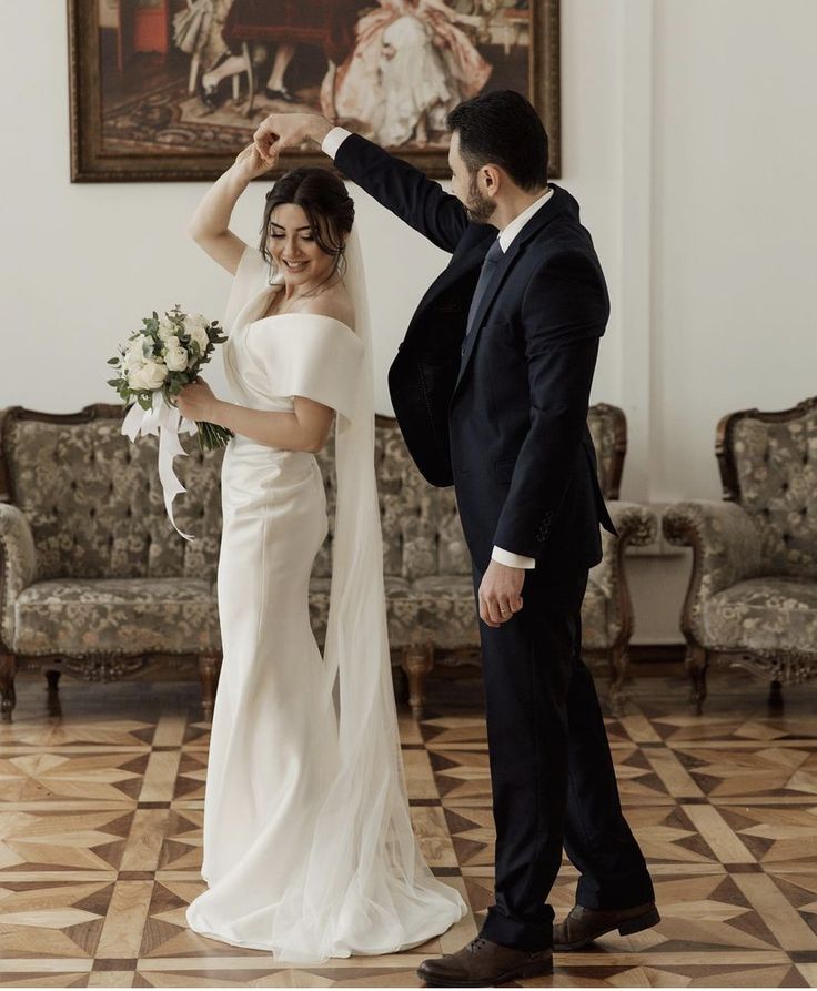 a bride and groom dancing together in front of a painting on the wall at their wedding reception