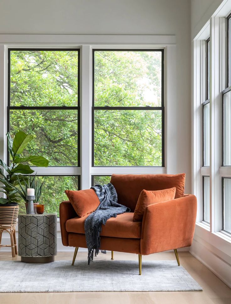 a living room filled with furniture and lots of window sill space next to a large potted plant