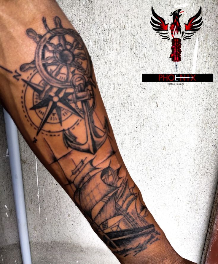 a man's arm with a ship and compass tattoo on it