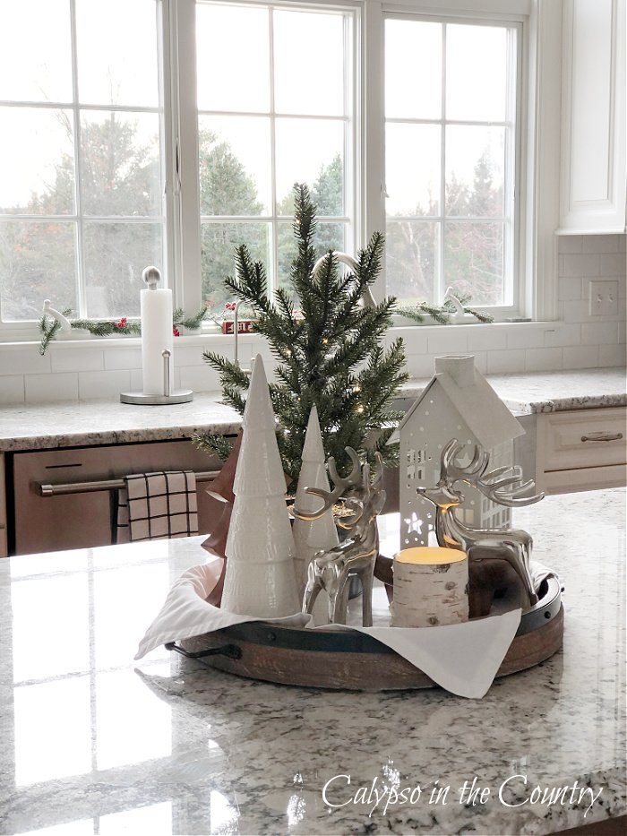 a christmas tree in a tray on a kitchen counter with other holiday decorations around it