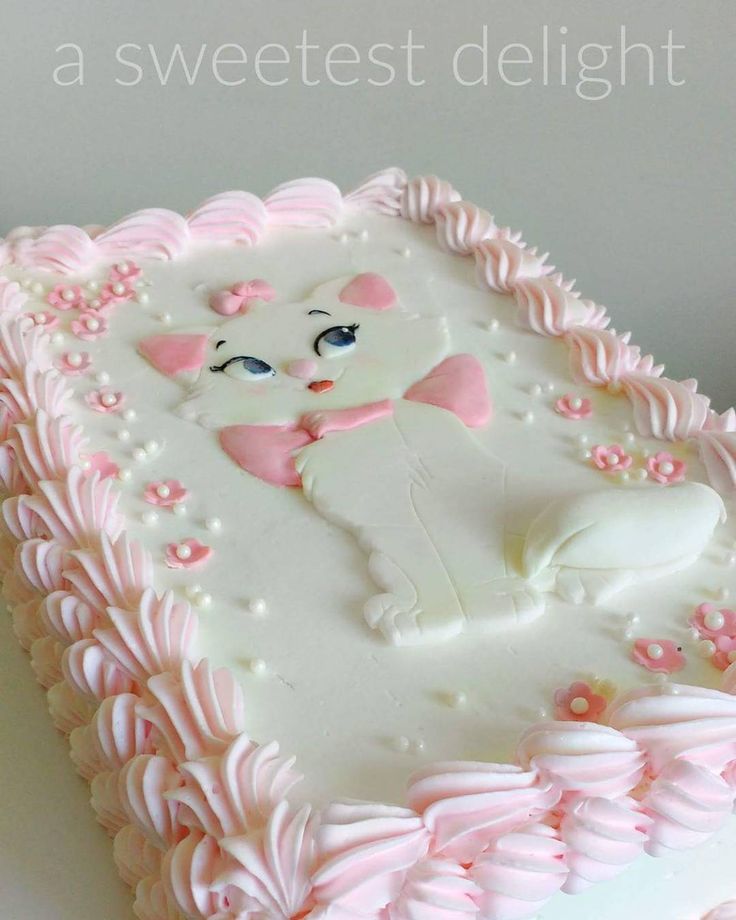 a white cake with pink icing and a cat on it