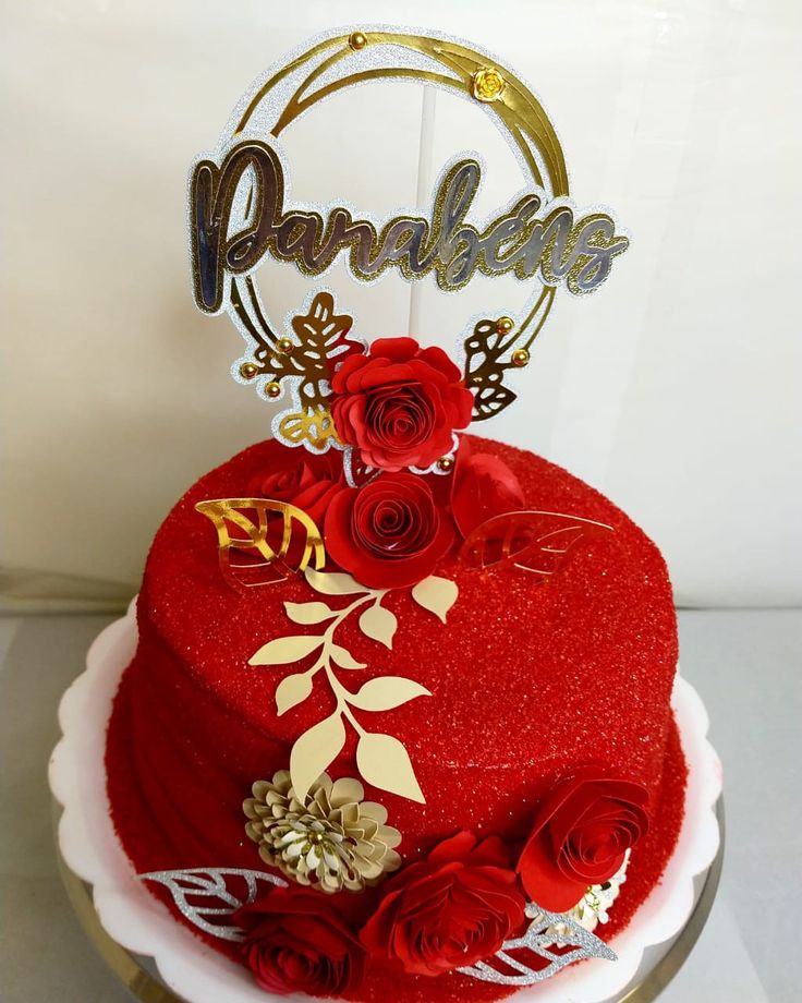 a heart shaped cake with roses on top and the word love spelled in gold letters