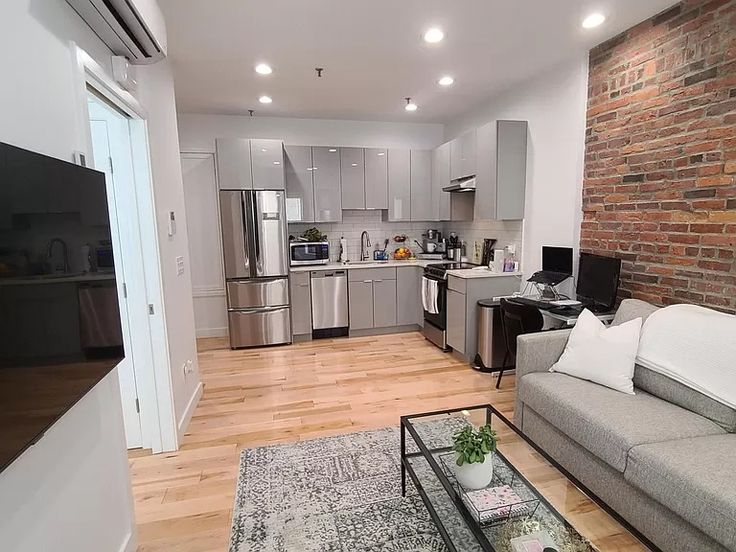 a living room filled with furniture next to a kitchen and dining room table on top of a hard wood floor