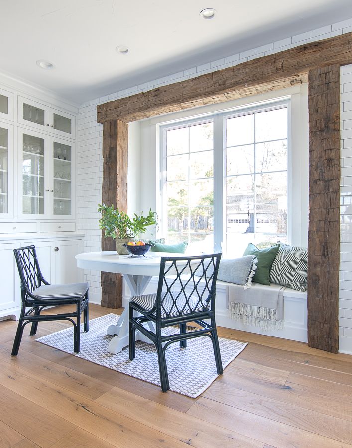 a dining room table with two chairs and a bench in front of a window that looks out onto the street