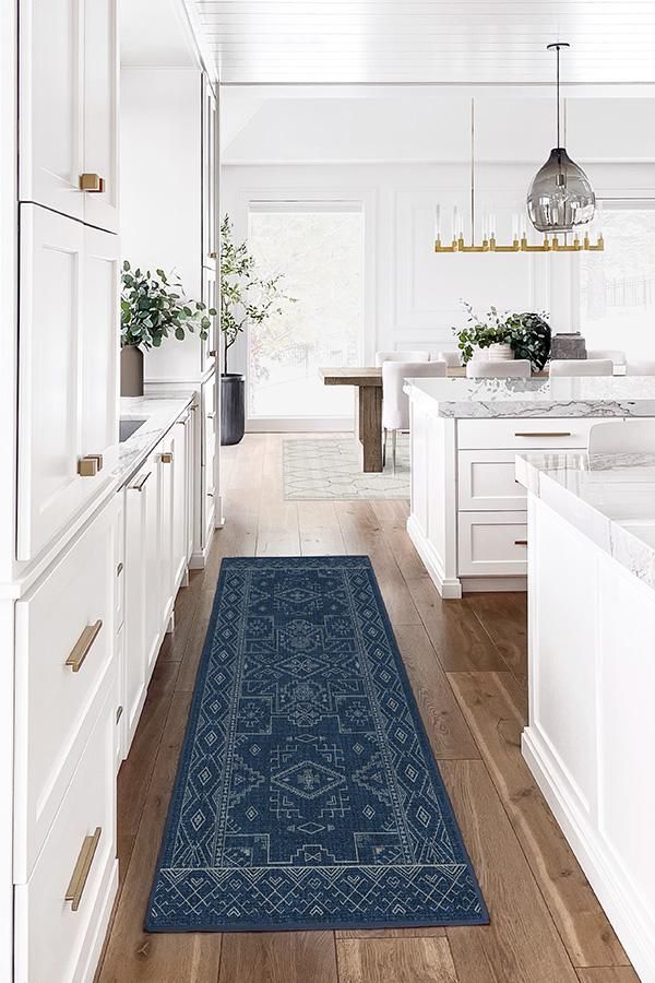 a blue rug is in the middle of a kitchen with white cabinets and counter tops