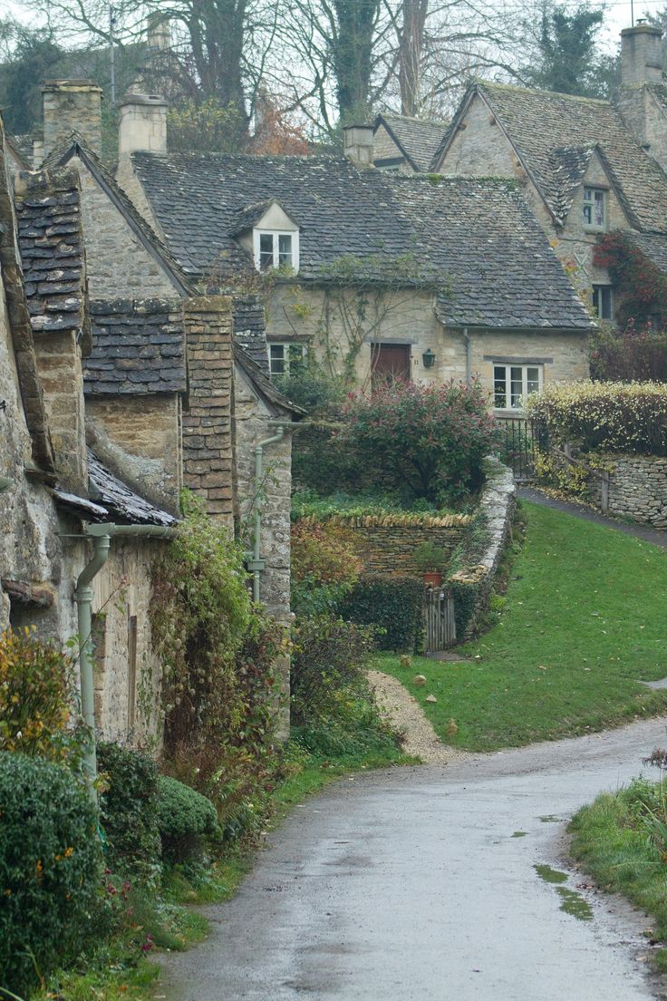 an alley way with stone buildings and green grass in the foreground, on a rainy day