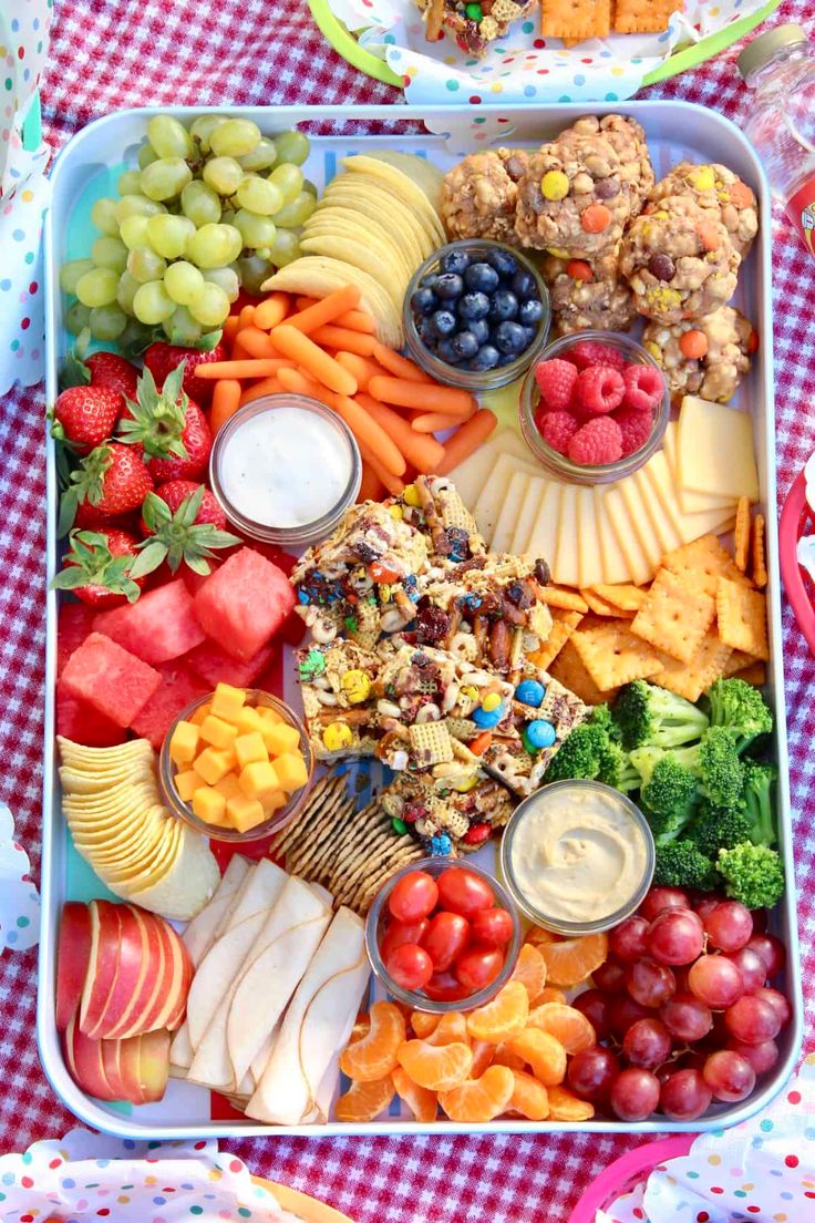 a tray filled with fruits and vegetables on top of a checkered tablecloth covered table