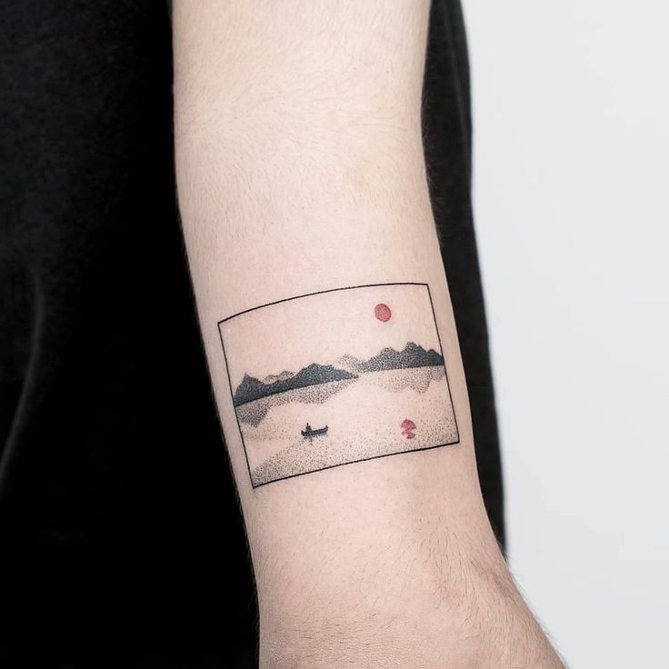 a man with a tattoo on his arm that has mountains and a boat in the water