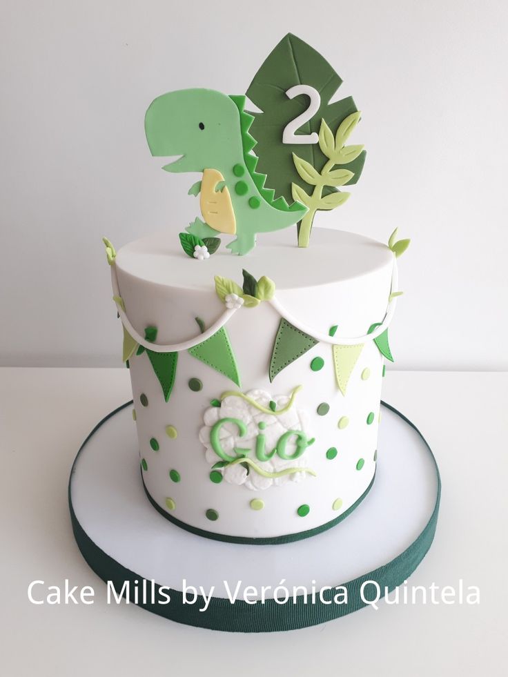 a birthday cake with a dinosaur on top and number two in the middle, sitting on a plate