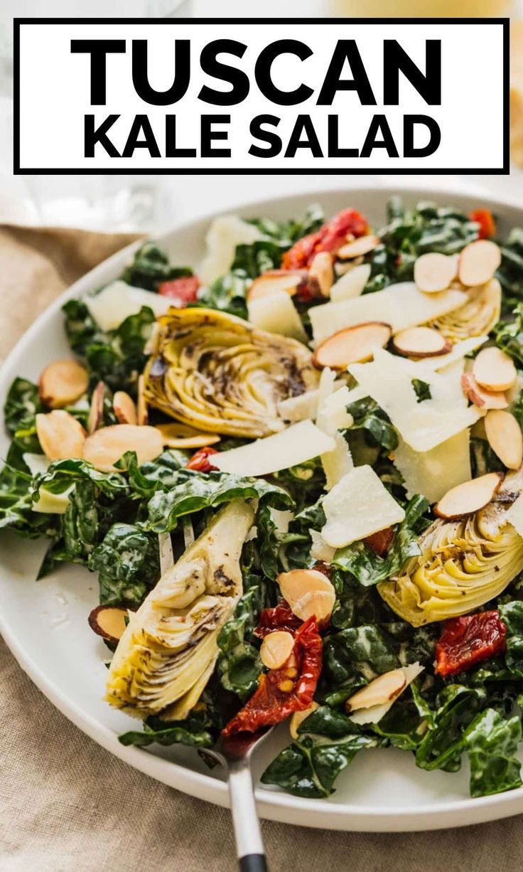 a white plate topped with kale salad covered in cheese and almonds next to a fork