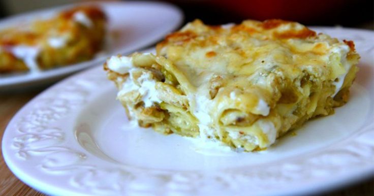 a piece of lasagna sitting on top of a white plate next to a red casserole dish