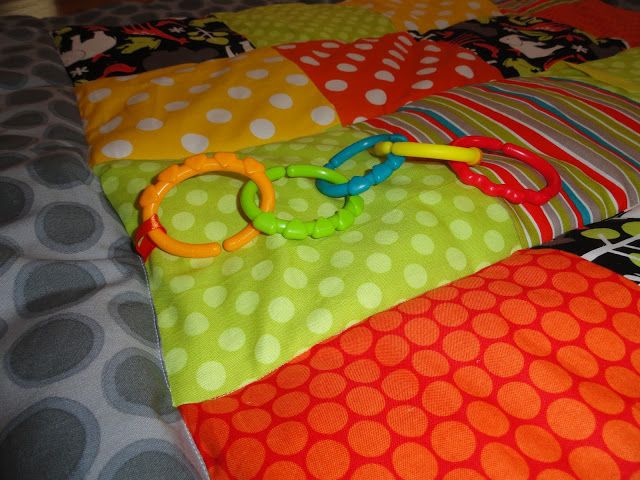 a baby toy laying on top of a colorful bedding with polka dots and circles