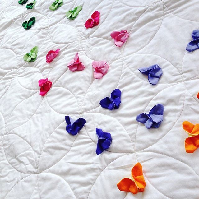 colorful paper butterflies are scattered on the white quilt