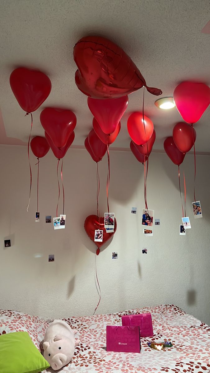 heart shaped balloons hang from the ceiling above a bed