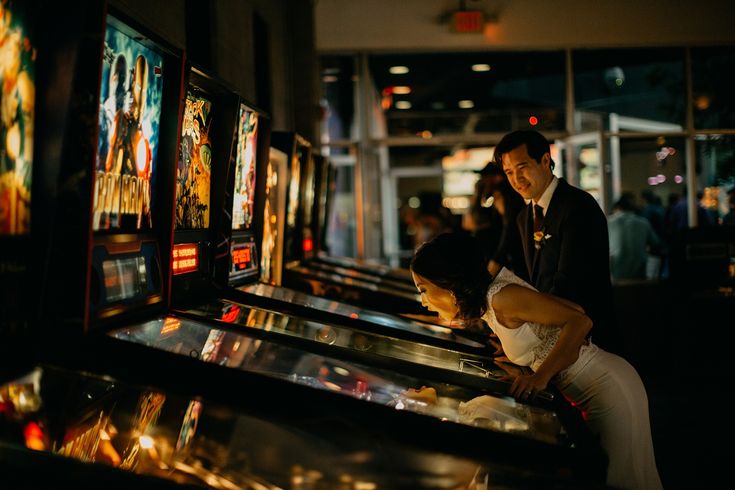 a man and woman standing next to each other in front of some pinball machines