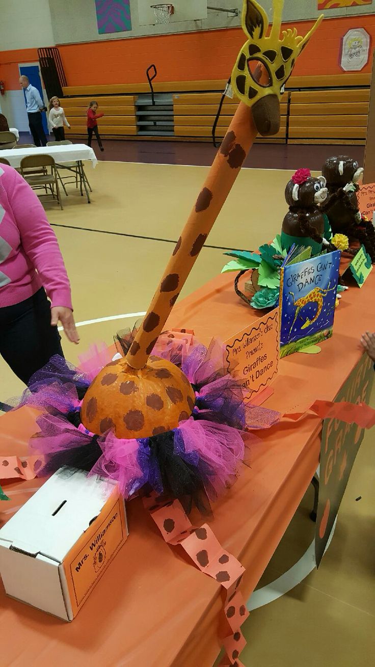 a woman standing next to a giraffe decoration on top of an orange table