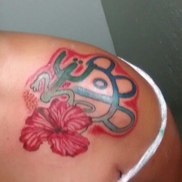 a woman with a tattoo on her shoulder has a pink flower and scissors in it