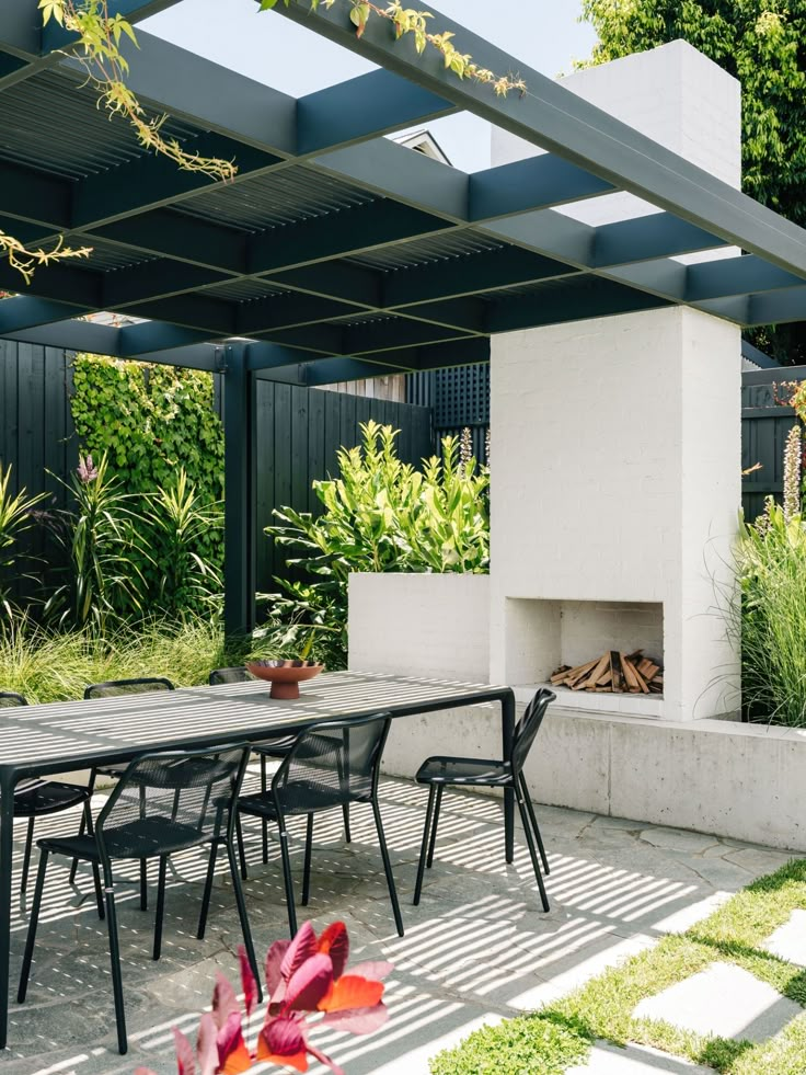 an outdoor dining area with table, chairs and fire place in the middle of it