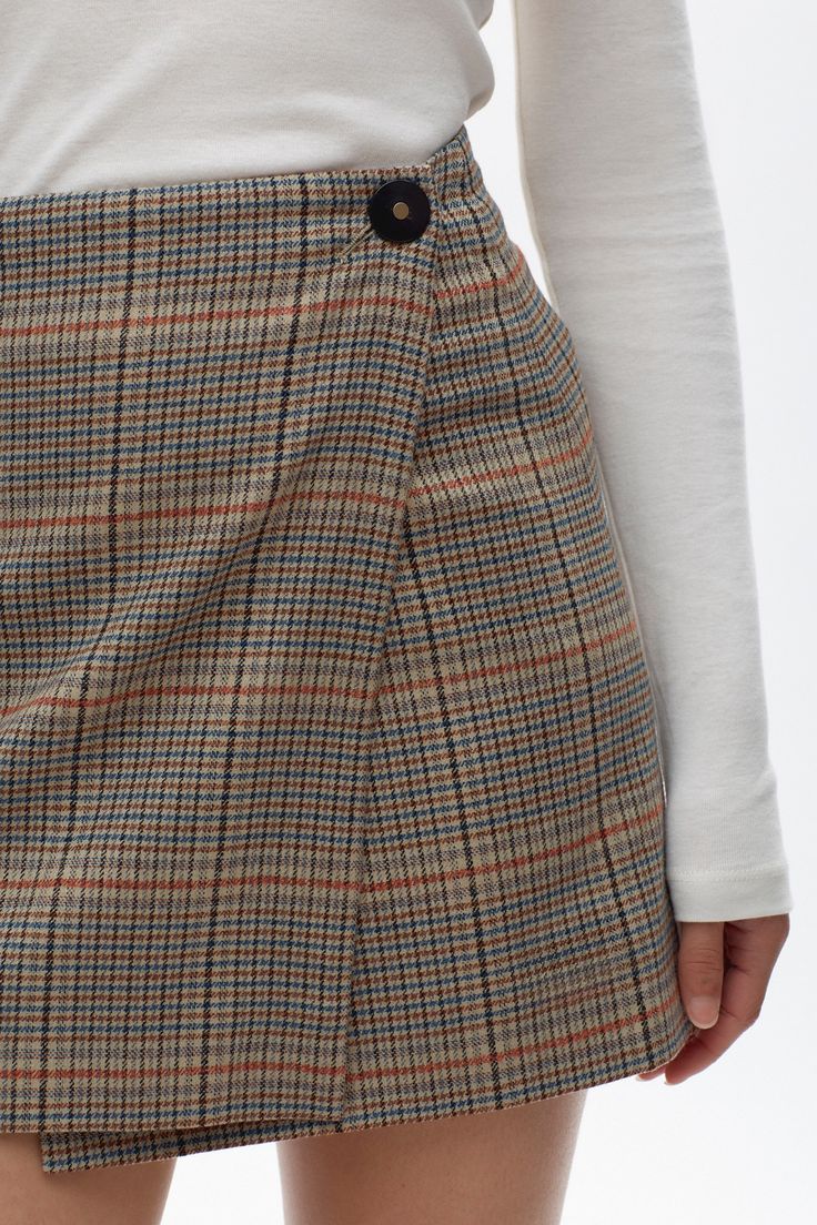 Our luxe take on the classic mini skirt. Crafted from premium wool and fully lined with 100% Cupro lining. The Rosetta Wool Skirt features a wrap-over closure, adorned with a decorative button on the exterior and a discreet hidden button on the interior, ensuring a snug and secure fit. Fall Skort With Button Closure For Workwear, Formal Fall Skirt With Buttons, Elegant Wrap Skirt For Fall Workwear, Workwear Mini Skirt With Button Closure For Winter, Workwear Skirt With Side Buttons, Fitted Asymmetrical Skort For Fall, Winter Mini Skirt With Button Closure For Workwear, Winter Workwear Mini Skirt With Button Closure, Workwear Mini Wrap Skirt For Fall