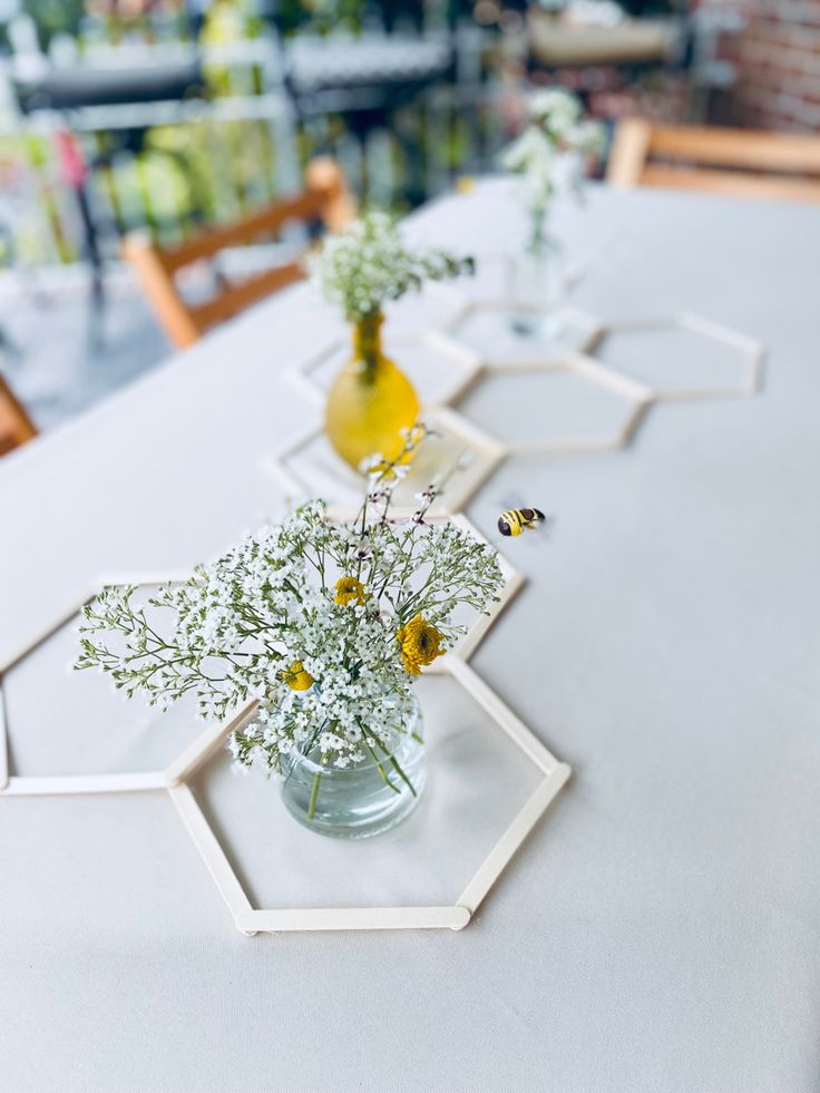 three vases filled with flowers sitting on top of a white table covered in paper