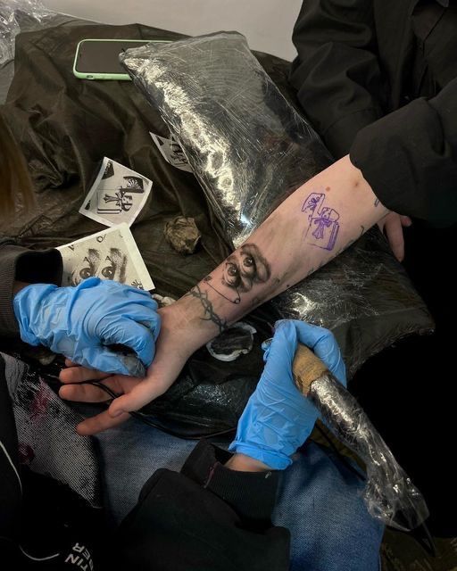 a man with a tattoo on his arm sitting in a chair next to another person