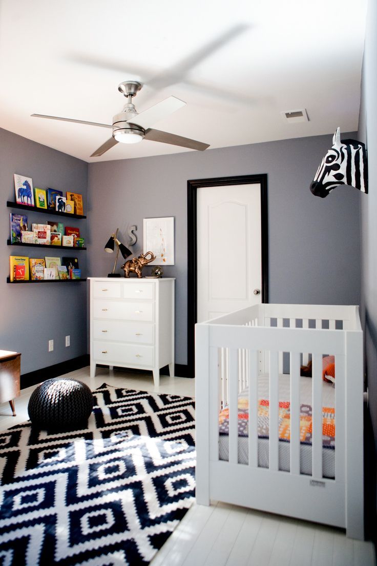 a baby's room with gray walls and black and white rugs on the floor