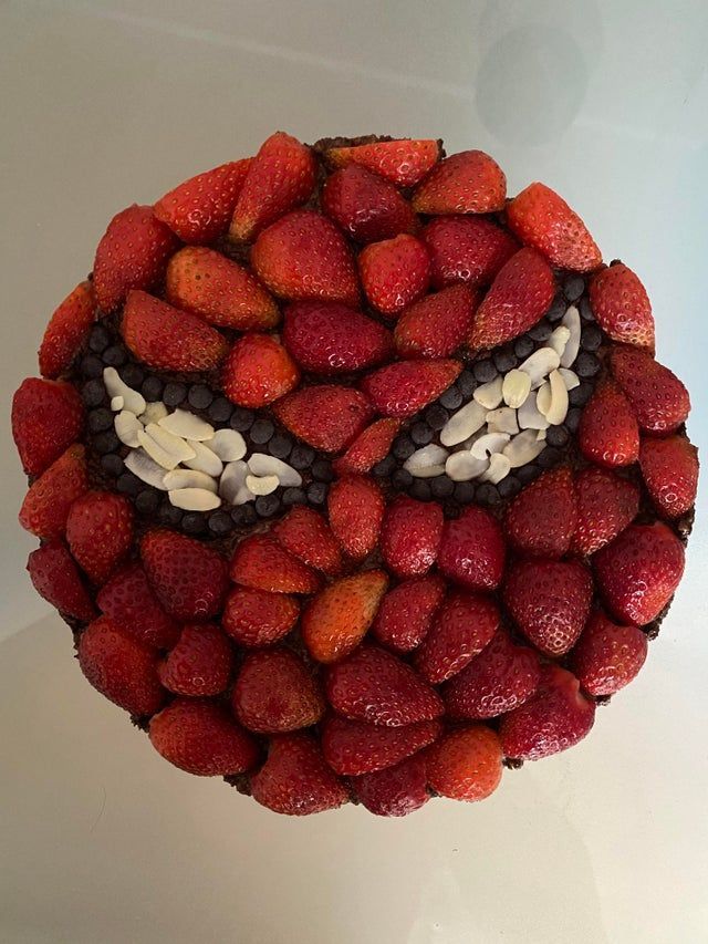 a cake made to look like a face with strawberries and chocolate chips on top