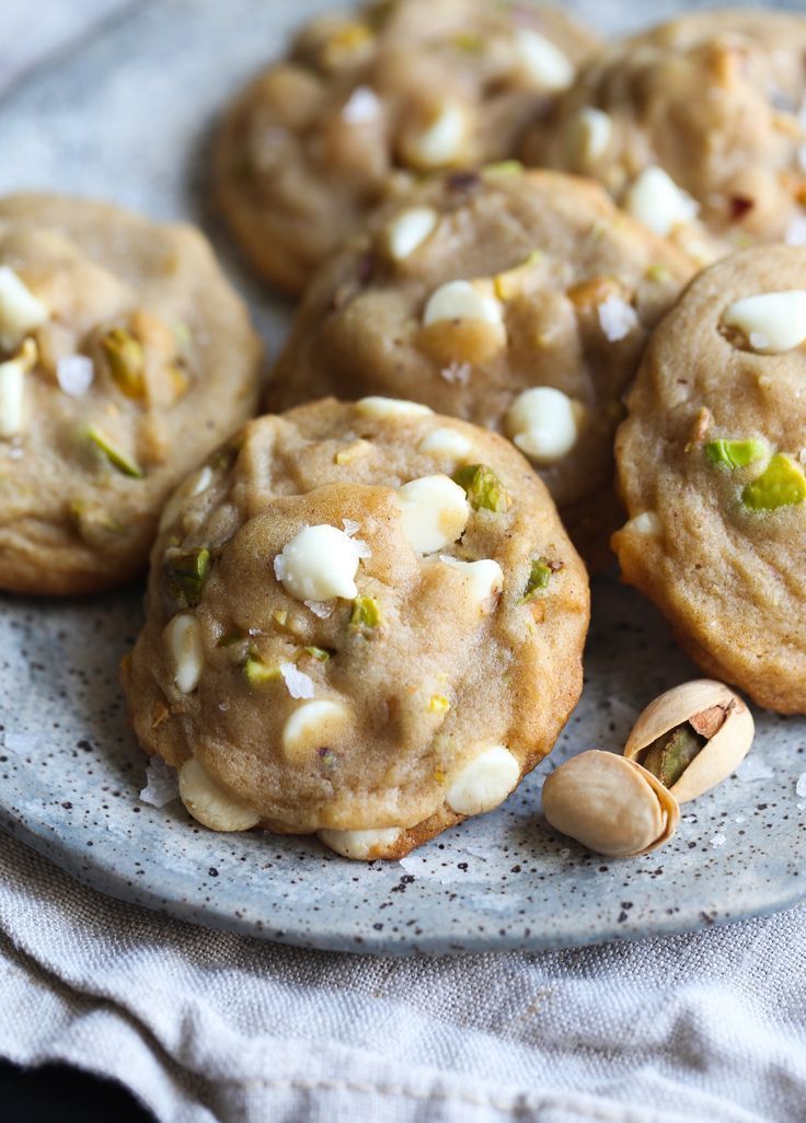 several cookies with white and green toppings sit on a plate next to a napkin