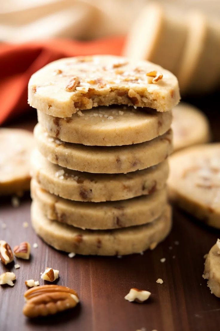 a stack of cookies sitting on top of a wooden table with pecans around it