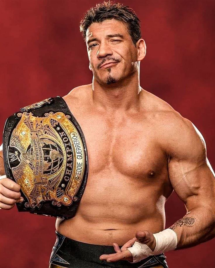 a man with no shirt on holding a wrestling belt in his hand and looking at the camera