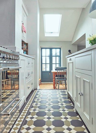 a kitchen with white cabinets and checkered flooring on the walls, along with a skylight