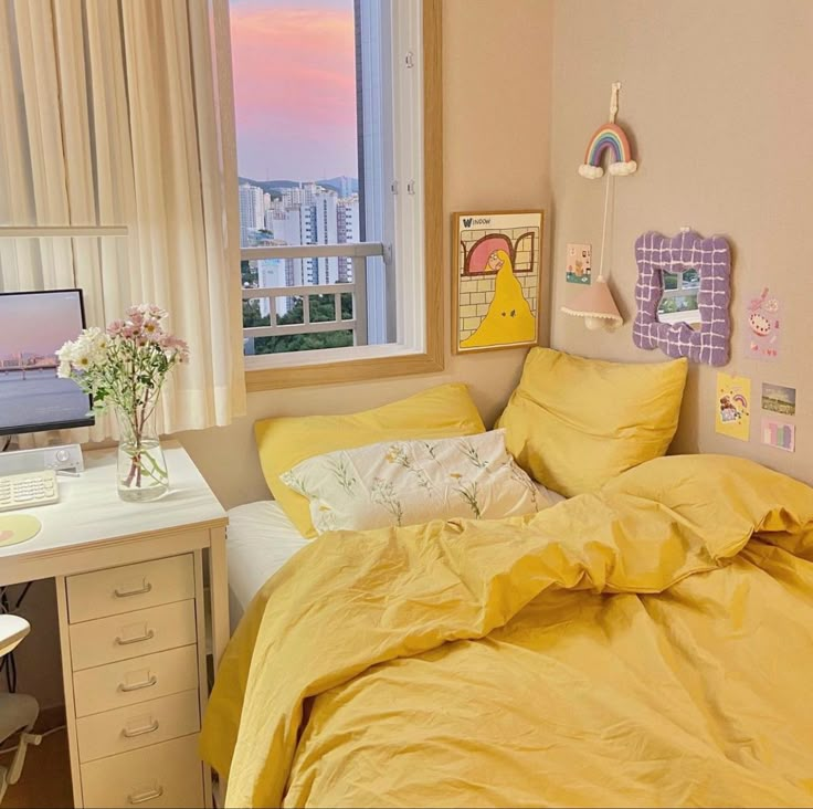 a bed with yellow sheets and pillows next to a window in a room that has a view of the city