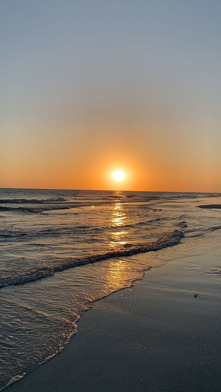 the sun is setting over the water at the beach