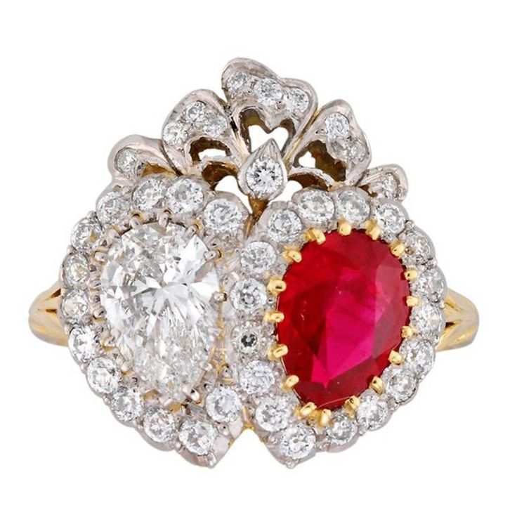 a red and white diamond ring with an oval shaped center surrounded by smaller round diamonds