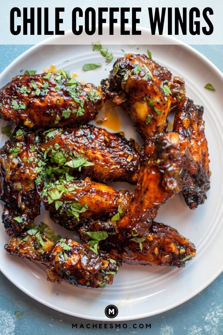 grilled chicken wings on a white plate with parsley sprinkled over them